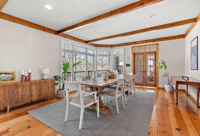 dining room with french doors, a textured ceiling, light wood-type flooring, beamed ceiling, and baseboards