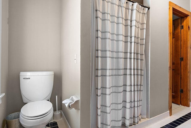 bathroom with a stall shower, toilet, and tile patterned floors