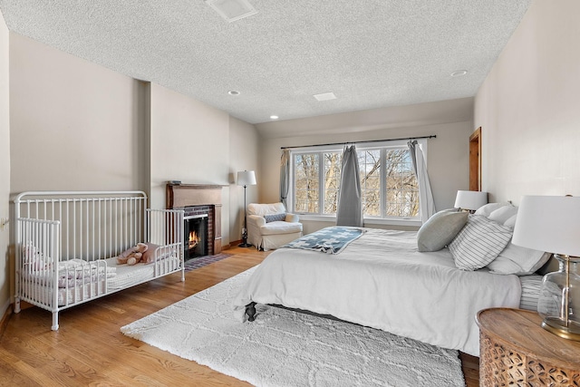 bedroom with a fireplace with flush hearth, a textured ceiling, and wood finished floors