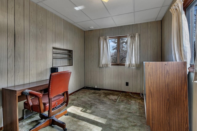 carpeted office space featuring a drop ceiling and wood walls