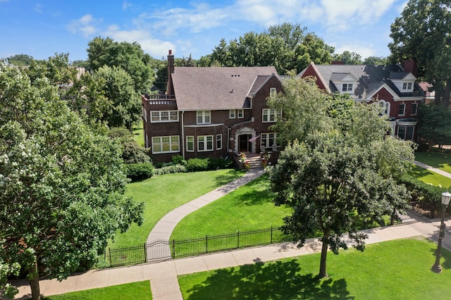 view of front facade with a front lawn, a fenced front yard, a balcony, brick siding, and a chimney