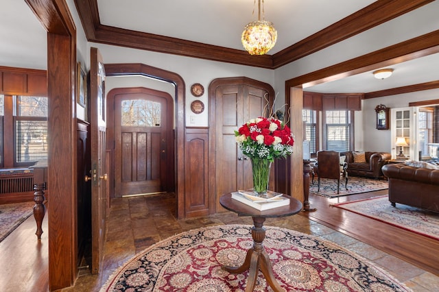 foyer entrance featuring arched walkways, a chandelier, and ornamental molding