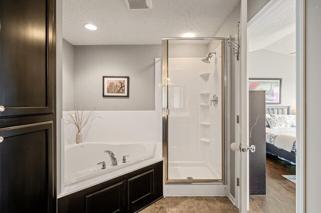 ensuite bathroom with visible vents, a shower stall, a garden tub, a textured ceiling, and ensuite bath