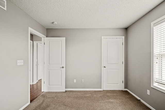 unfurnished bedroom with baseboards, multiple windows, and carpet floors