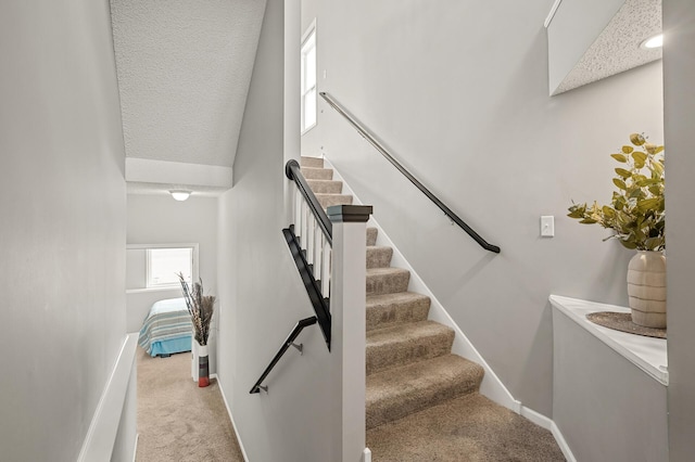 staircase featuring baseboards and carpet