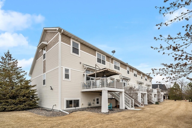 back of house featuring stairs, a deck, and a yard