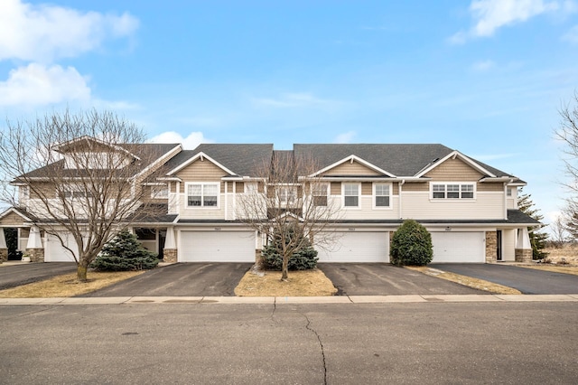 multi unit property featuring a garage, stone siding, and driveway