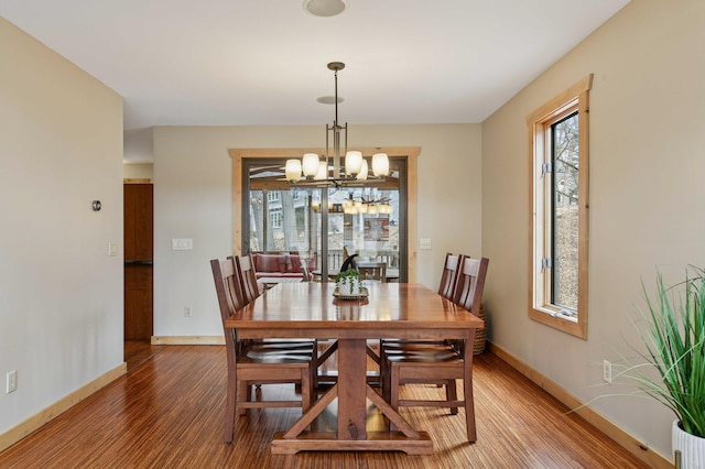 dining room featuring a notable chandelier, light wood finished floors, and baseboards