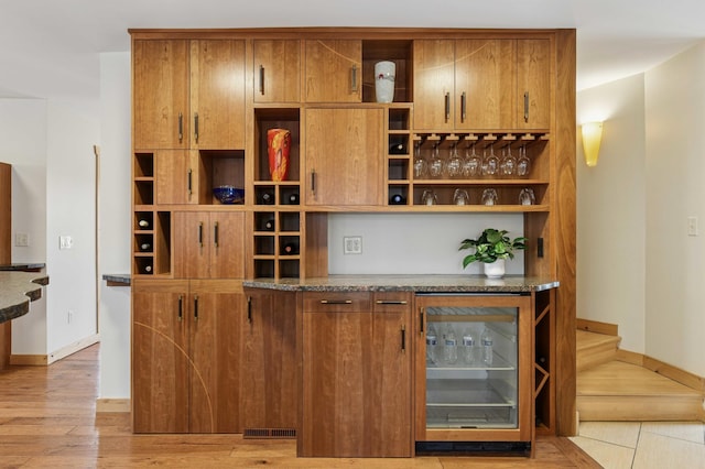 bar featuring beverage cooler, light wood finished floors, visible vents, and baseboards