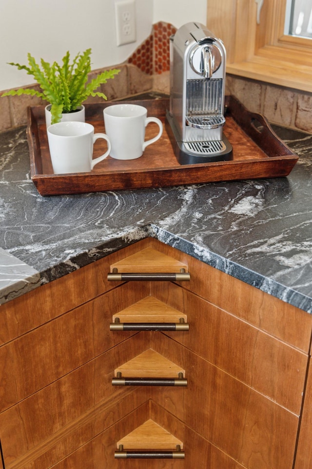 interior details with brown cabinets and dark stone countertops