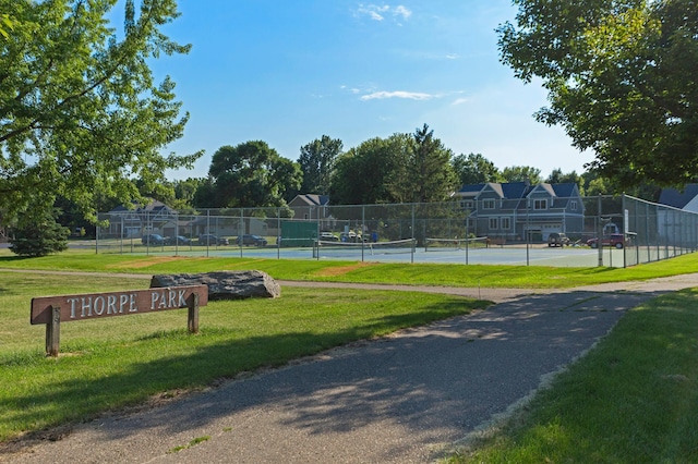 view of home's community featuring a tennis court, fence, and a lawn