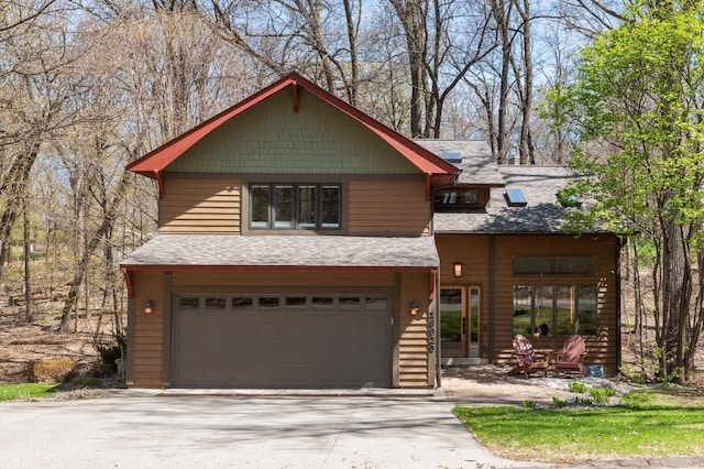rustic home featuring a shingled roof, an attached garage, and concrete driveway