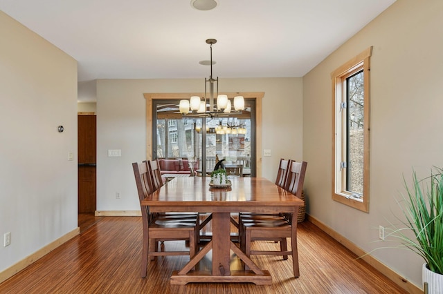 dining space featuring baseboards, an inviting chandelier, and light wood-style floors