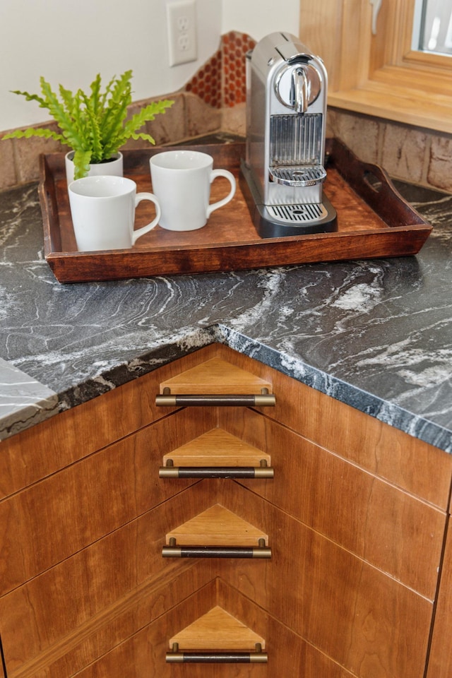 interior details with dark stone counters and brown cabinetry