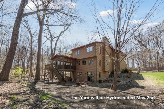 back of property featuring a sunroom, a wooden deck, and stairs