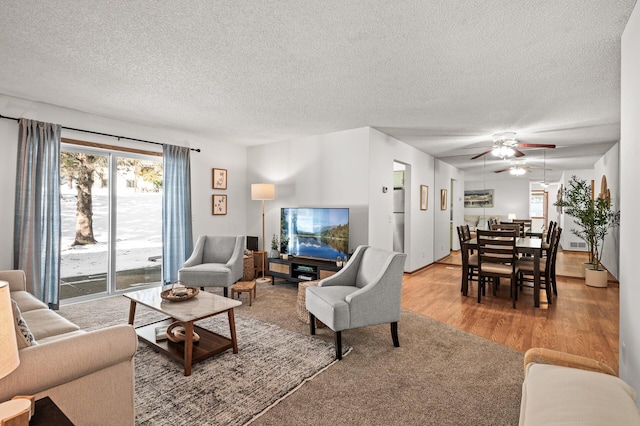 living room with hardwood / wood-style flooring, ceiling fan, and a textured ceiling