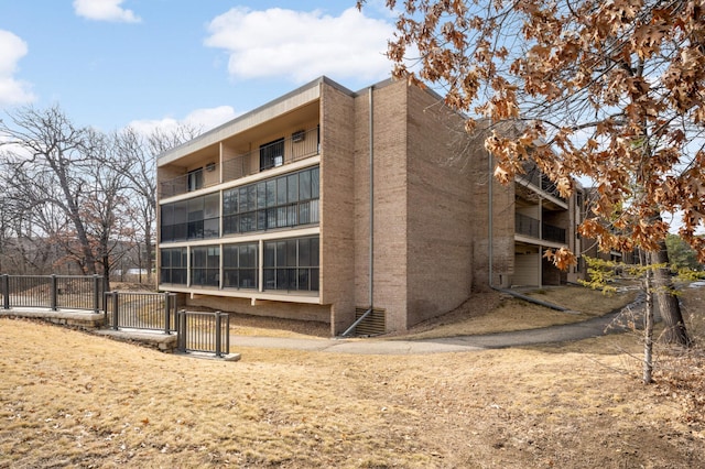 rear view of property featuring fence and brick siding