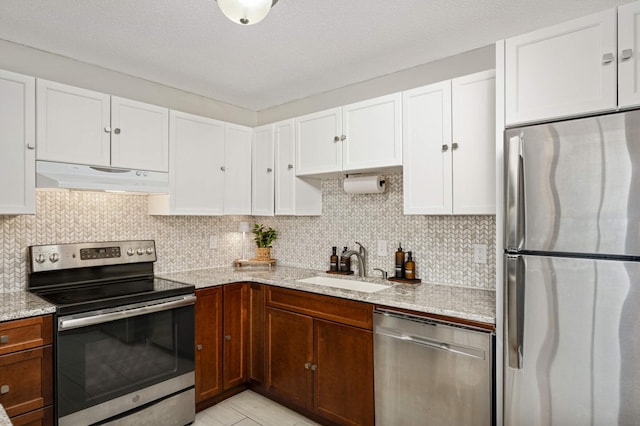 kitchen with under cabinet range hood, decorative backsplash, appliances with stainless steel finishes, and a sink