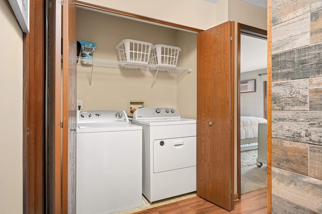 washroom with laundry area, independent washer and dryer, an AC wall unit, and light wood-type flooring