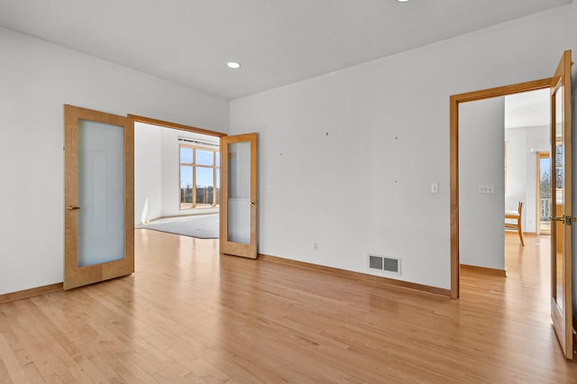 spare room with visible vents, light wood-style flooring, french doors, and baseboards