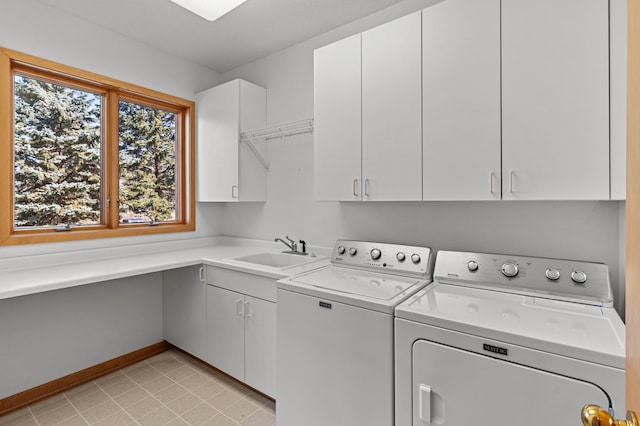 washroom featuring separate washer and dryer, cabinet space, baseboards, and a sink