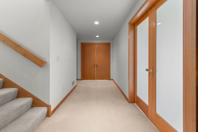 hallway featuring recessed lighting, light colored carpet, stairs, and baseboards