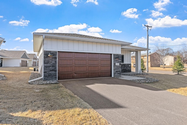 view of front facade with aphalt driveway, stone siding, and board and batten siding