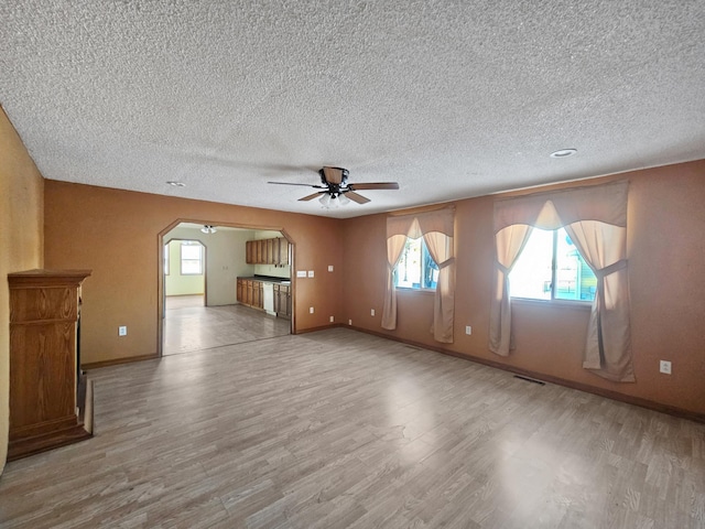 unfurnished living room featuring ceiling fan, light hardwood / wood-style floors, and a textured ceiling