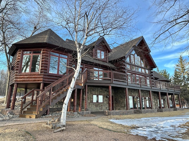 view of front of house with stairway, log siding, a shingled roof, stone siding, and a deck