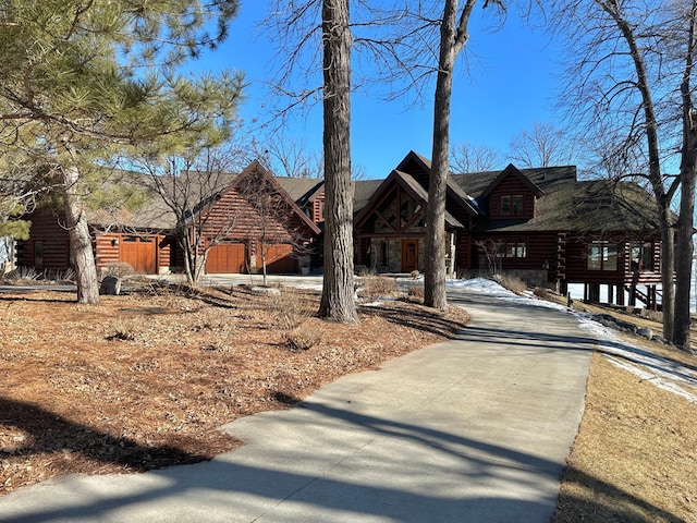 log-style house featuring log siding and concrete driveway