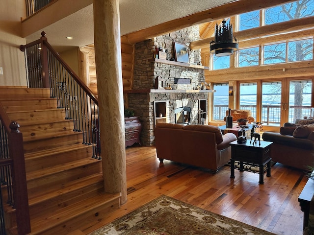 living area featuring hardwood / wood-style flooring, a textured ceiling, stairway, a high ceiling, and a fireplace