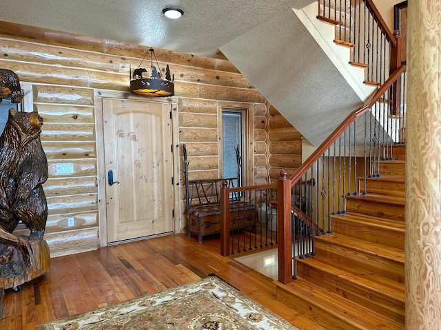 foyer entrance featuring vaulted ceiling, a textured ceiling, stairs, and hardwood / wood-style flooring