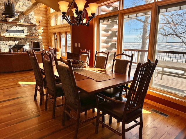 dining area featuring visible vents, plenty of natural light, log walls, and wood-type flooring