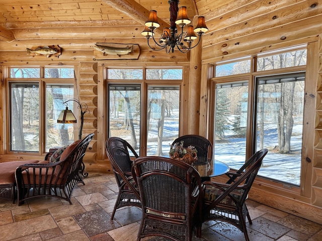 dining space with rustic walls, a chandelier, and stone tile flooring