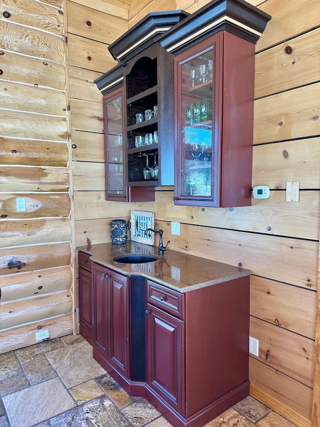 bar with a sink, log walls, and stone tile floors