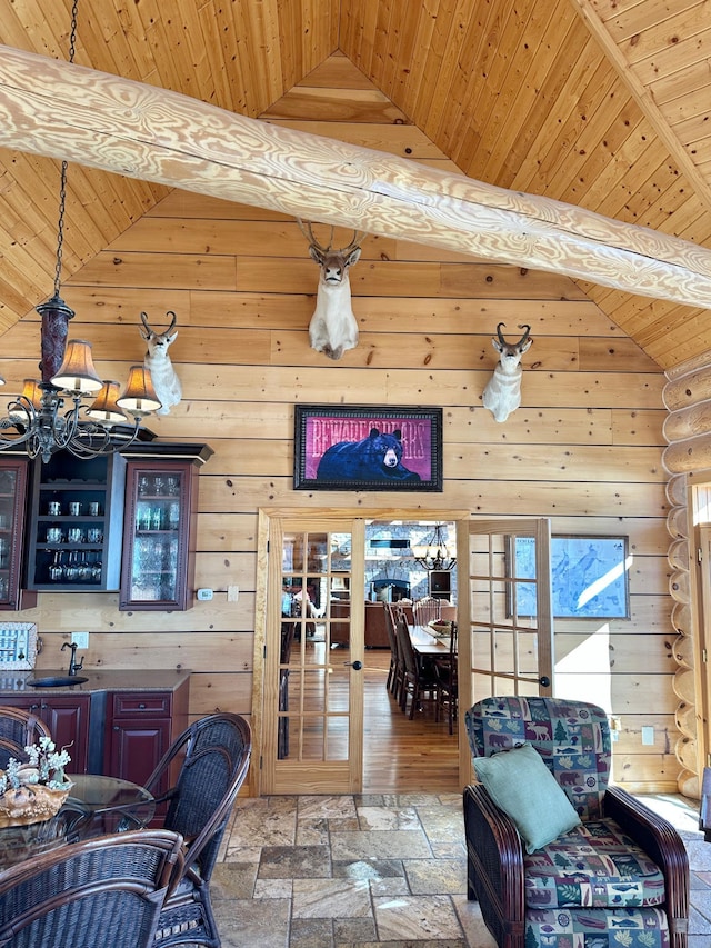 interior space featuring a chandelier, high vaulted ceiling, wood ceiling, and stone finish flooring