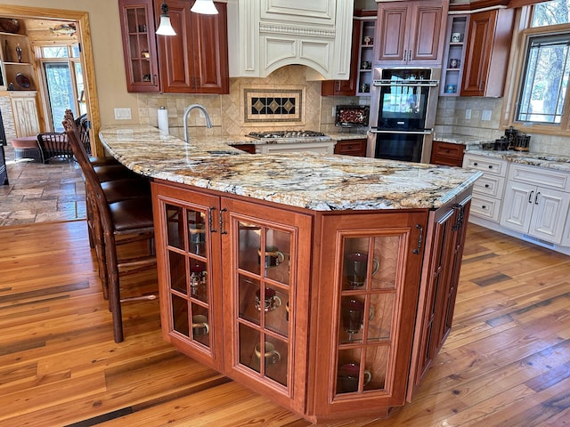 kitchen with light wood-style flooring, open shelves, a sink, stainless steel appliances, and light stone countertops