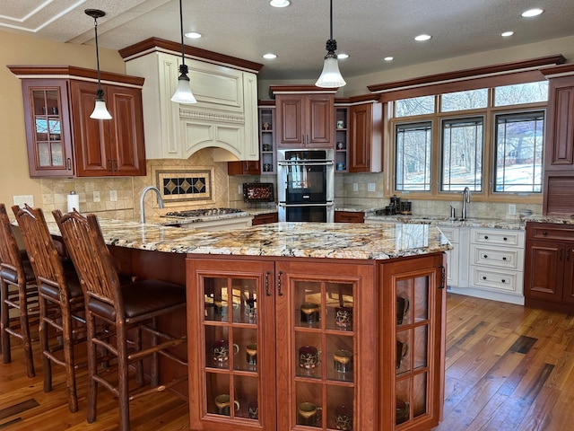 kitchen with glass insert cabinets, light stone counters, light wood-style floors, stainless steel appliances, and open shelves