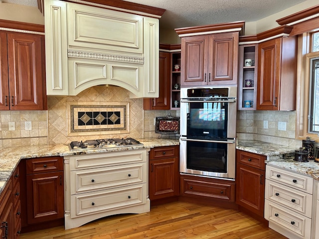 kitchen with open shelves, light wood-style flooring, cream cabinetry, and appliances with stainless steel finishes