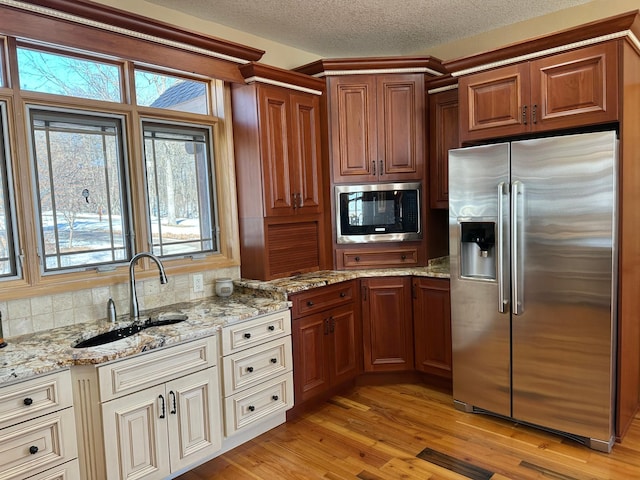 kitchen featuring a sink, a healthy amount of sunlight, light wood-style floors, and stainless steel appliances