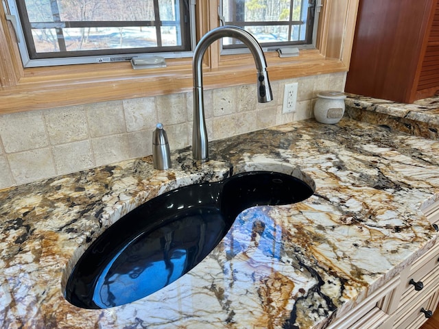 interior details featuring light stone countertops, backsplash, and a sink