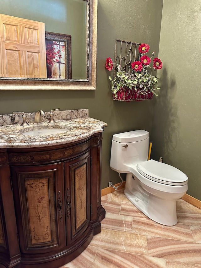 bathroom featuring toilet, vanity, and baseboards