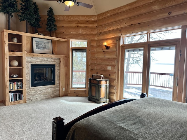 bedroom featuring high vaulted ceiling, a glass covered fireplace, rustic walls, carpet, and access to exterior