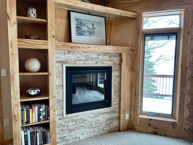 details with a glass covered fireplace, built in features, and carpet floors