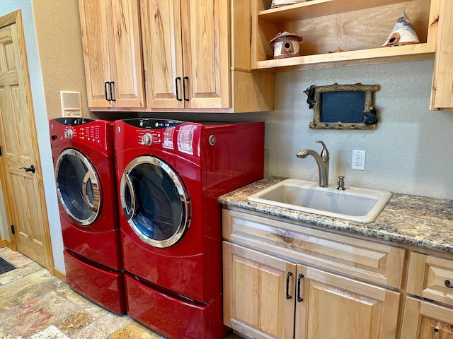 washroom with a sink, cabinet space, a textured wall, and washer and dryer