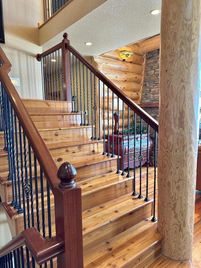 stairway featuring rustic walls, recessed lighting, a textured ceiling, and wood finished floors