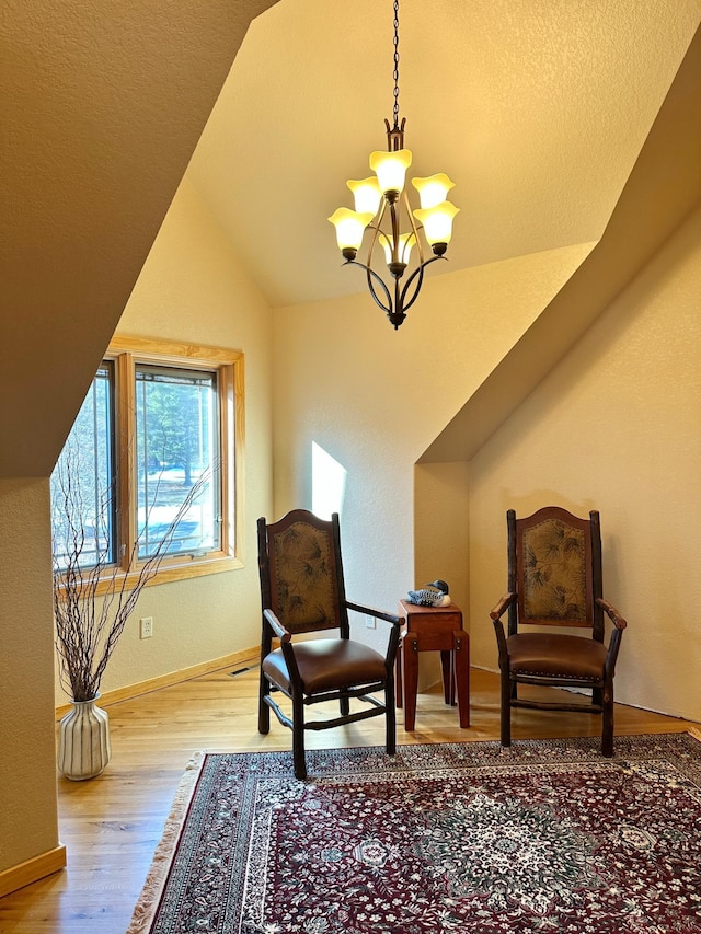 living area featuring a chandelier, vaulted ceiling, baseboards, and wood finished floors