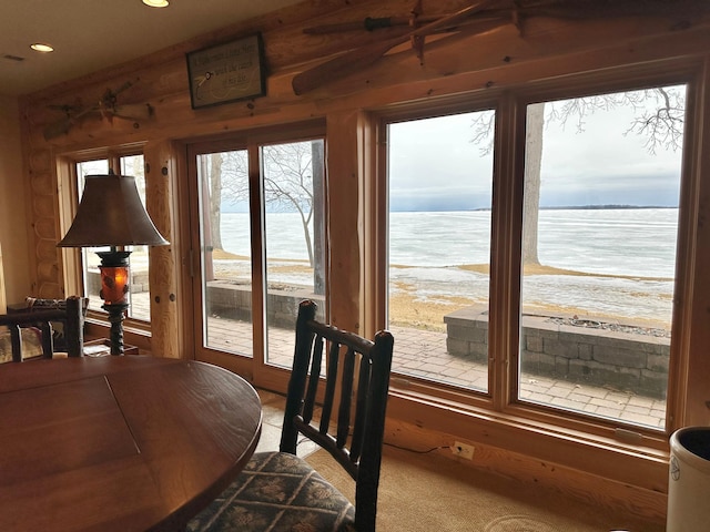 dining area with recessed lighting, log walls, and a water view