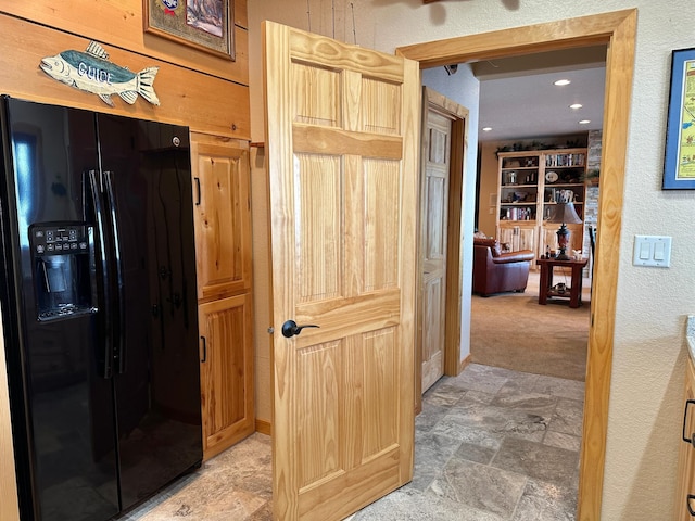 corridor with stone finish floor, recessed lighting, a textured wall, and light colored carpet