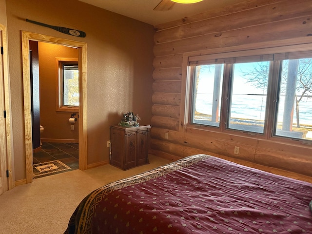 bedroom featuring connected bathroom, light colored carpet, baseboards, and rustic walls